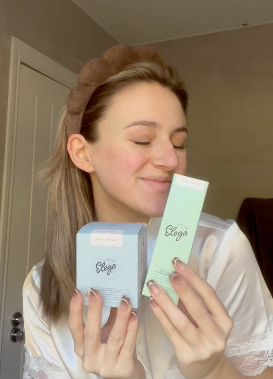 Person holding a box of night cream against a plain background.