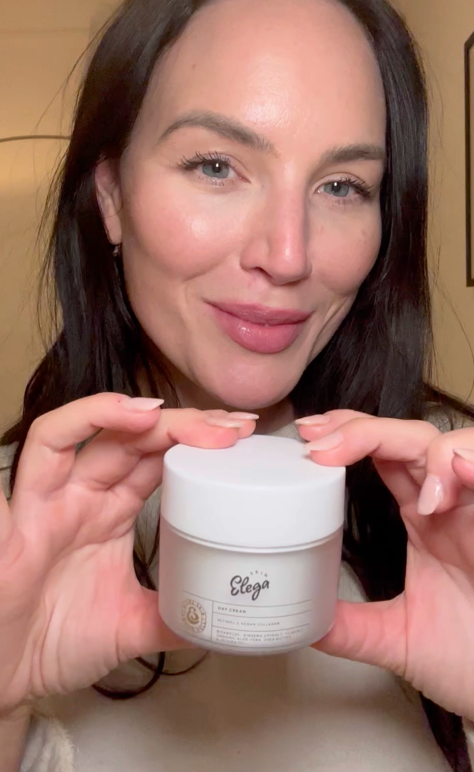 Person holding a box of night cream against a plain background.